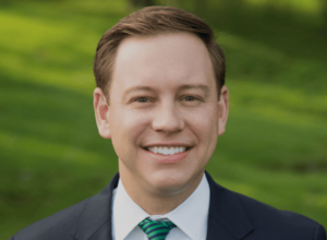 Man smiling wear dark blue suit with green striped tie