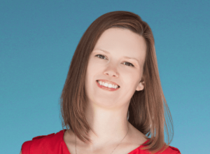 A woman with brown hair wearing a red shirt smiling