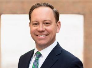 Man smiling wearing a navy blue suit with a tie